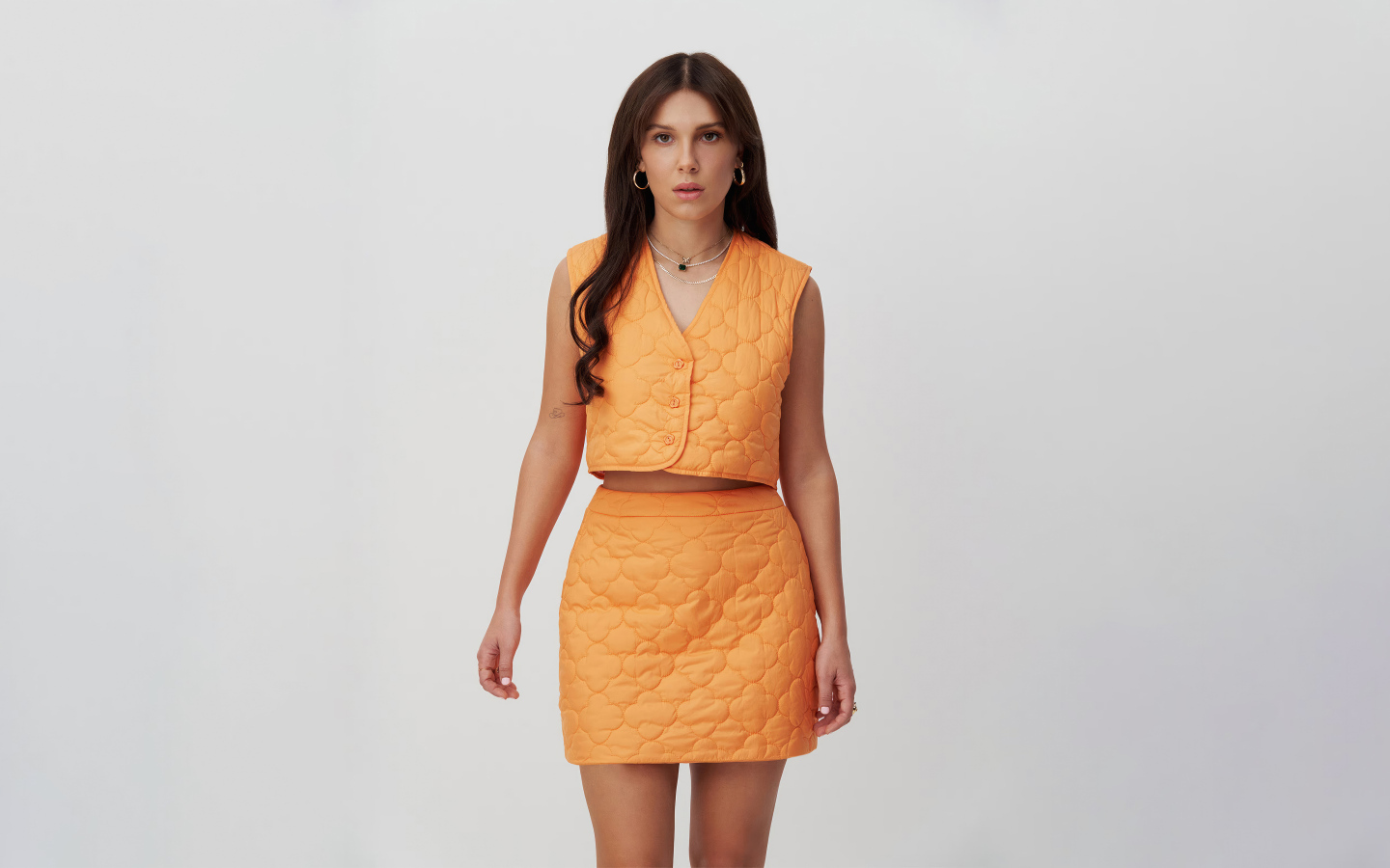 Девушка актриса Милли Бобби Браун в костюме на сером фоне