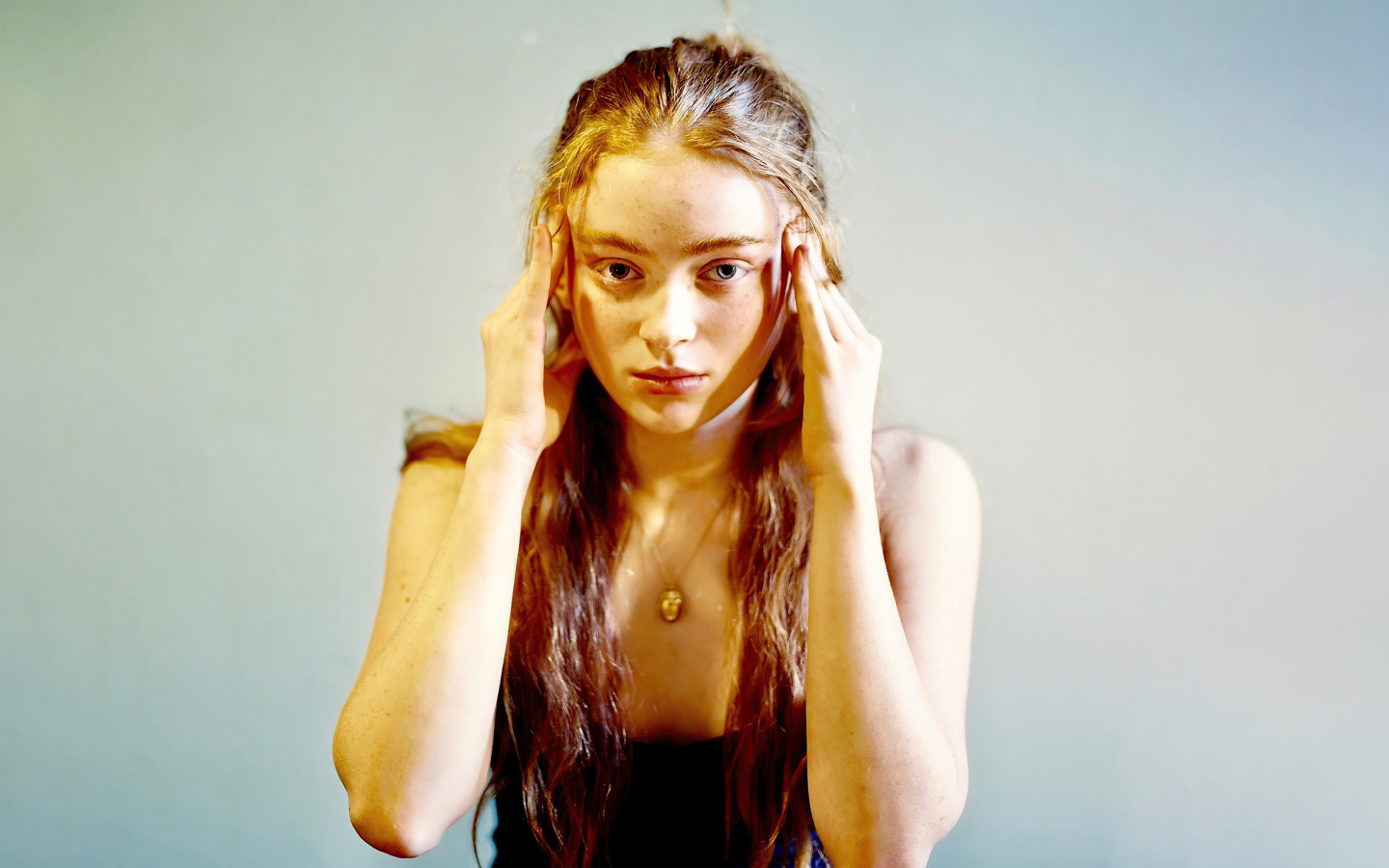 Рыжеволосая американская актриса Сэди Синк на сером фоне