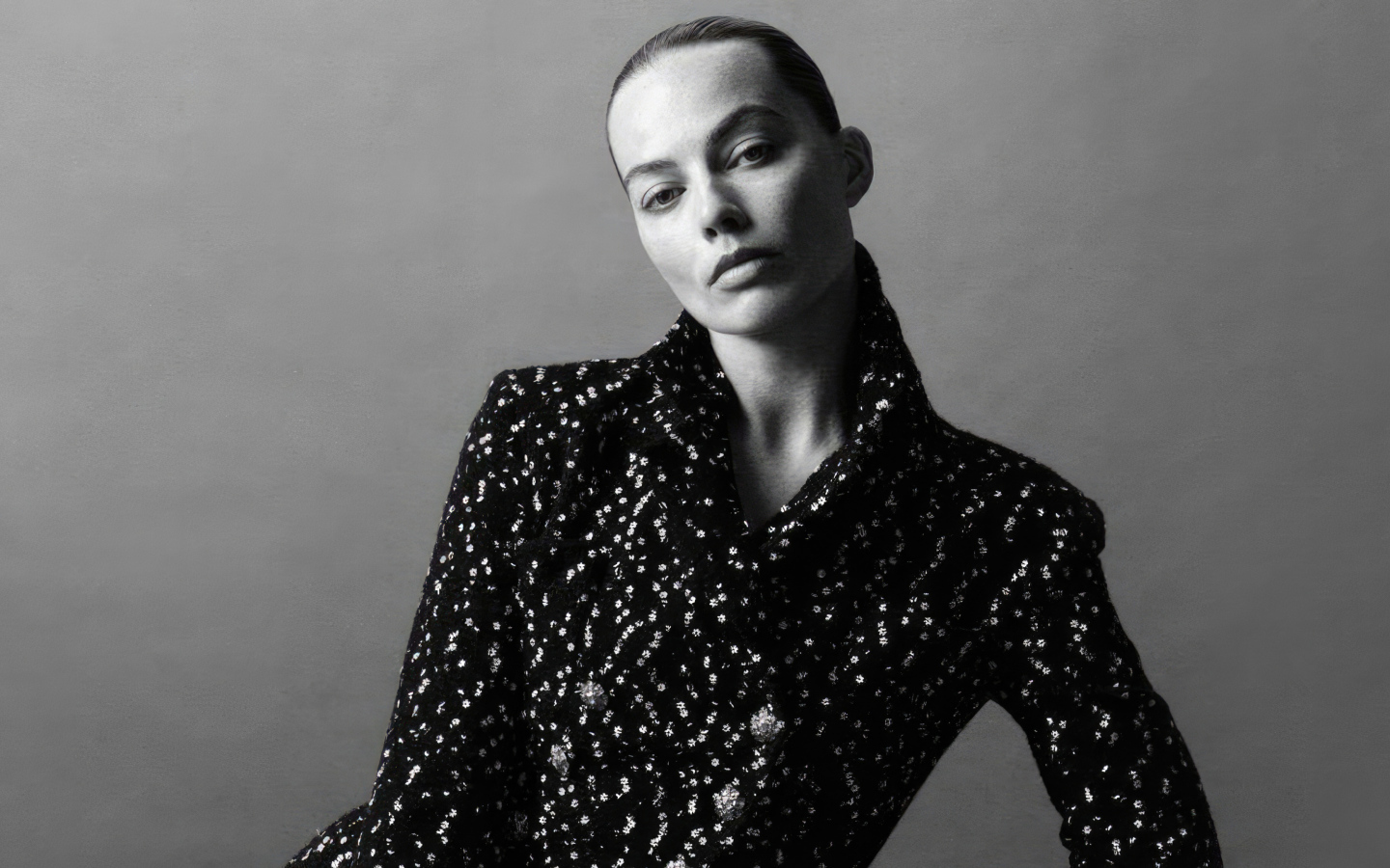 Грустная Марго Робби в блестящем пиджаке на сером фоне