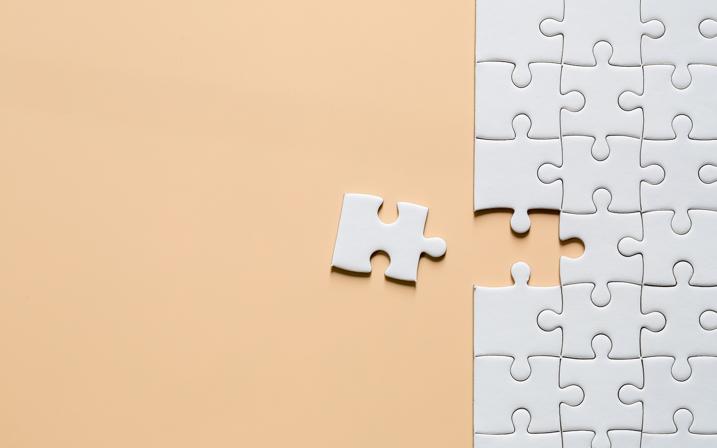 Белый пазл собирают на бежевом фоне