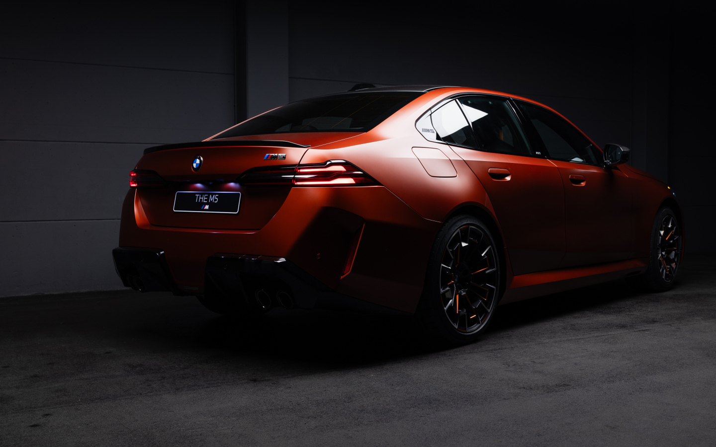 Вид сзади на красный автомобиль BMW M5 2025 года