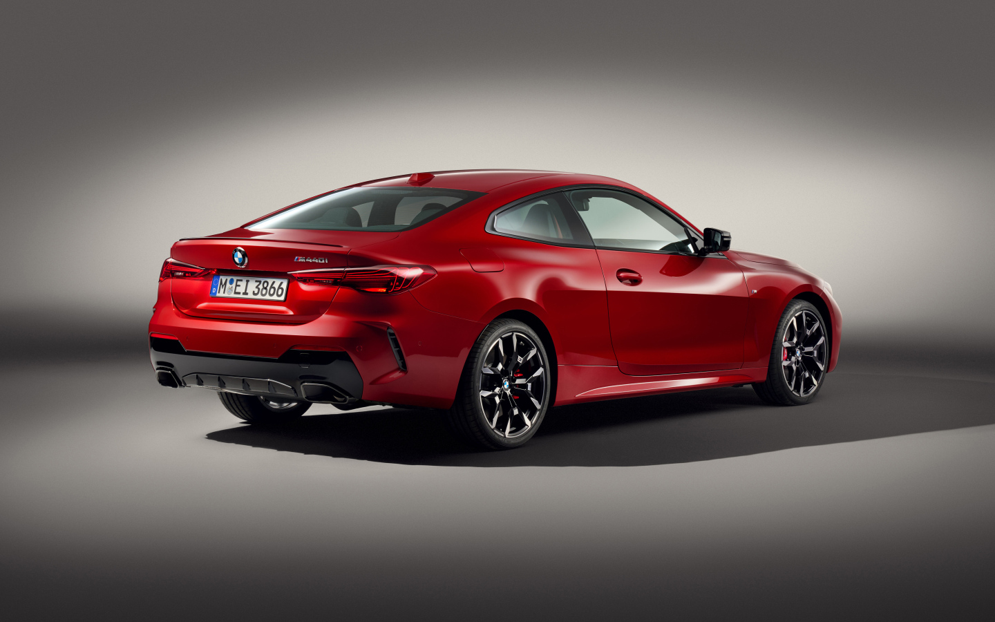 Красный автомобиль BMW M440i XDrive Coupé 2024 года на сером фоне