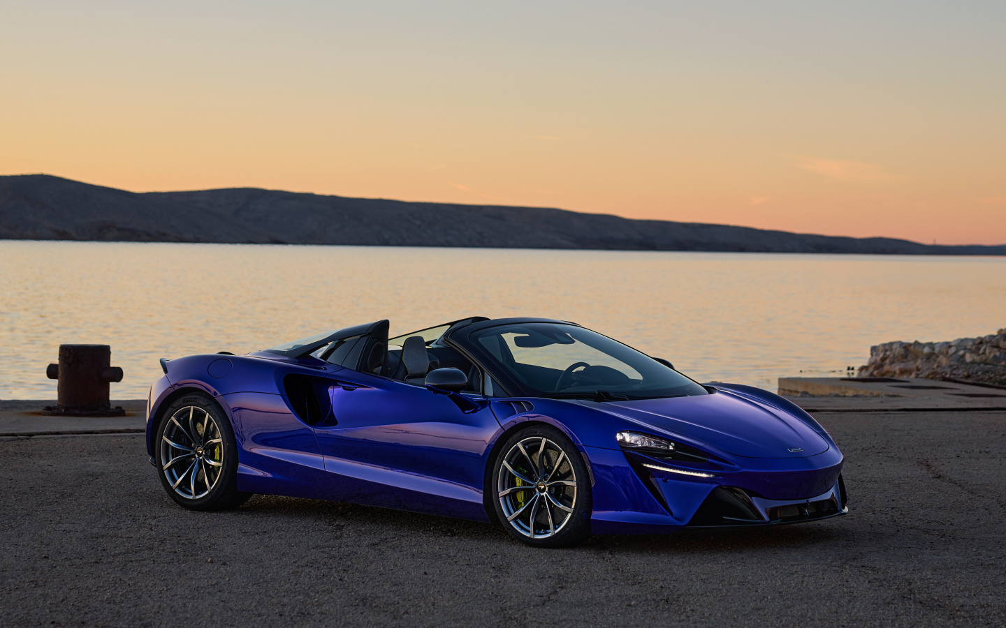 Синий быстрый автомобиль McLaren Artura Spider у воды