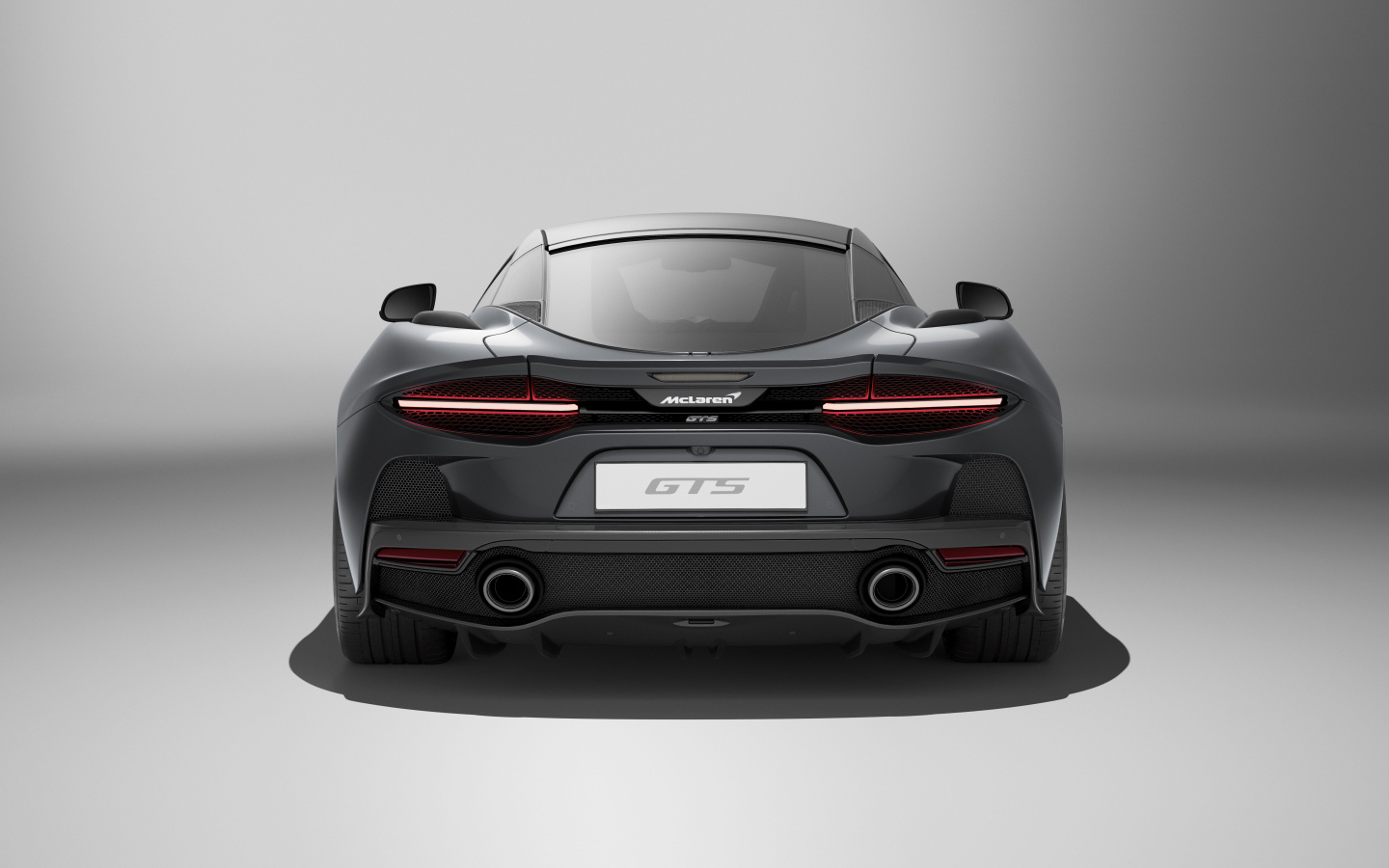 Вид сзади на автомобиль McLaren GTS на сером фоне