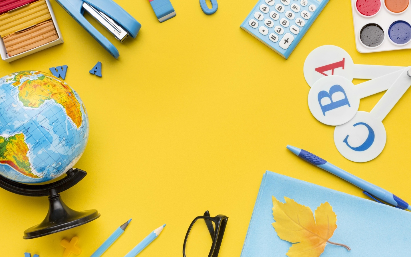 Красивые канцелярские предметы и глобус на желтом фоне