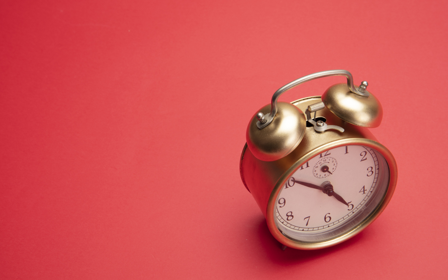 Золотой будильник на красном фоне
