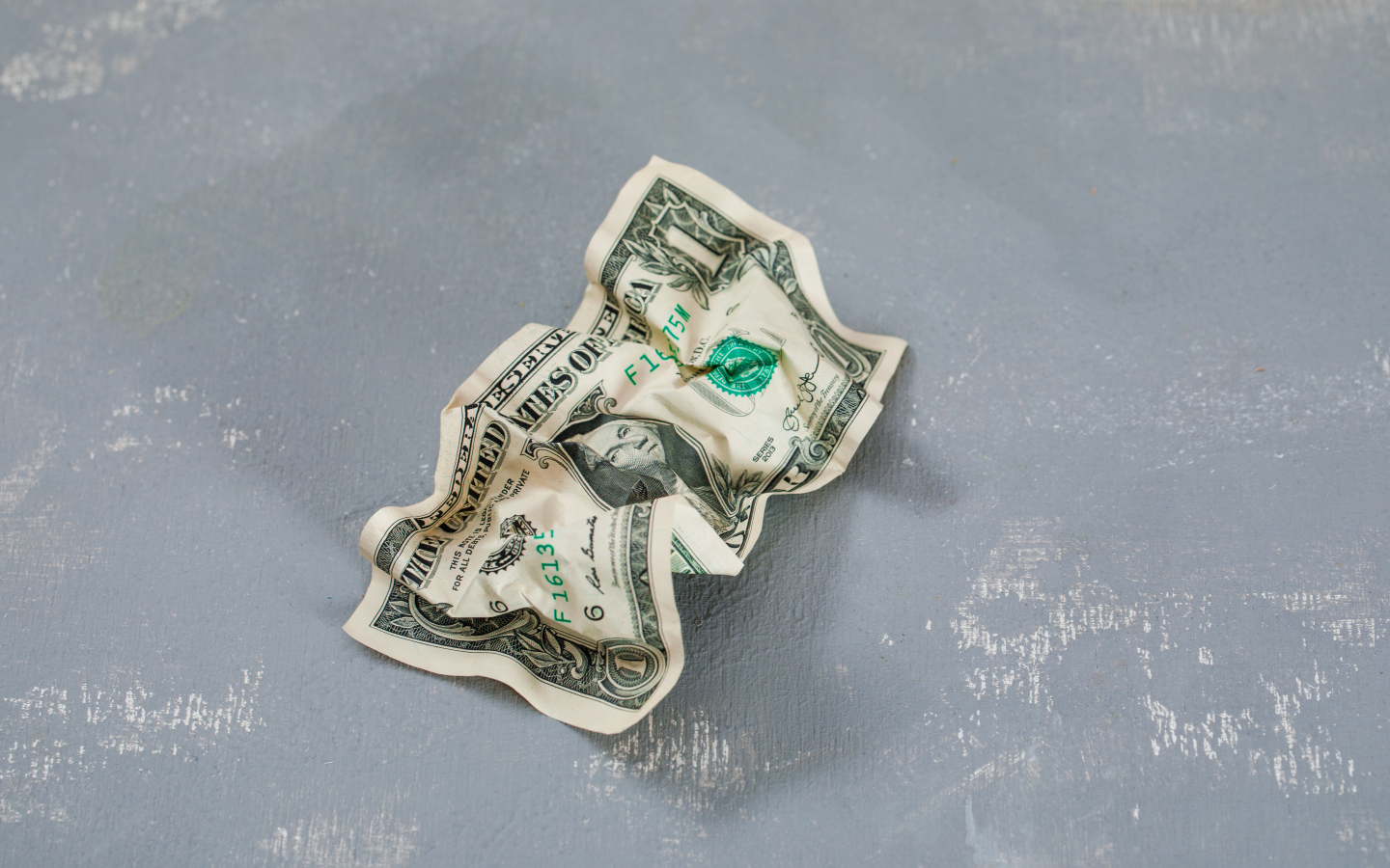 Смятая купюра один доллар на сером столе