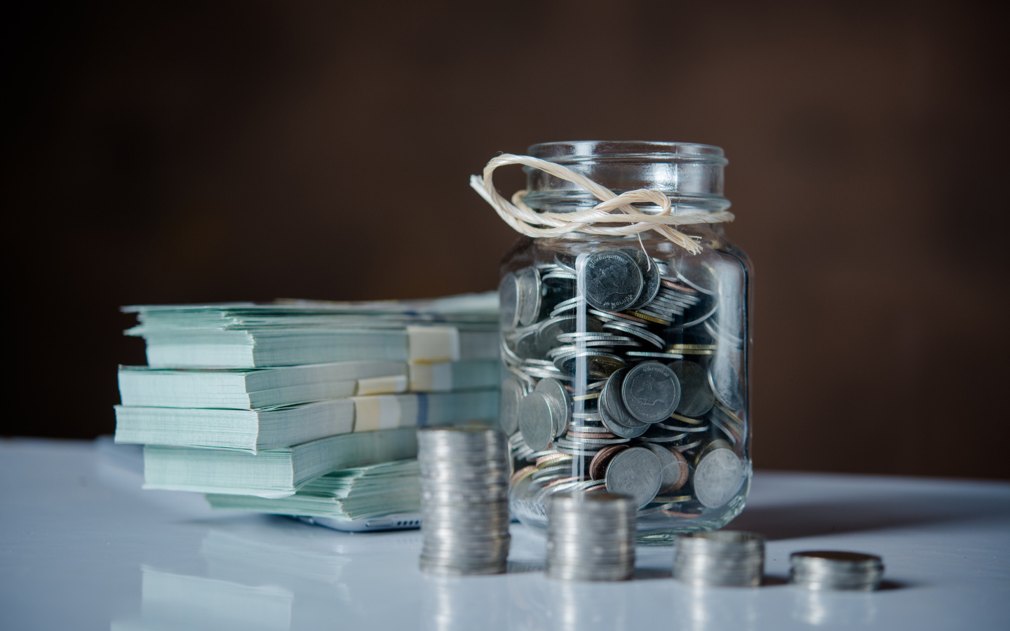 Банка с монетами на столе с пачками денег