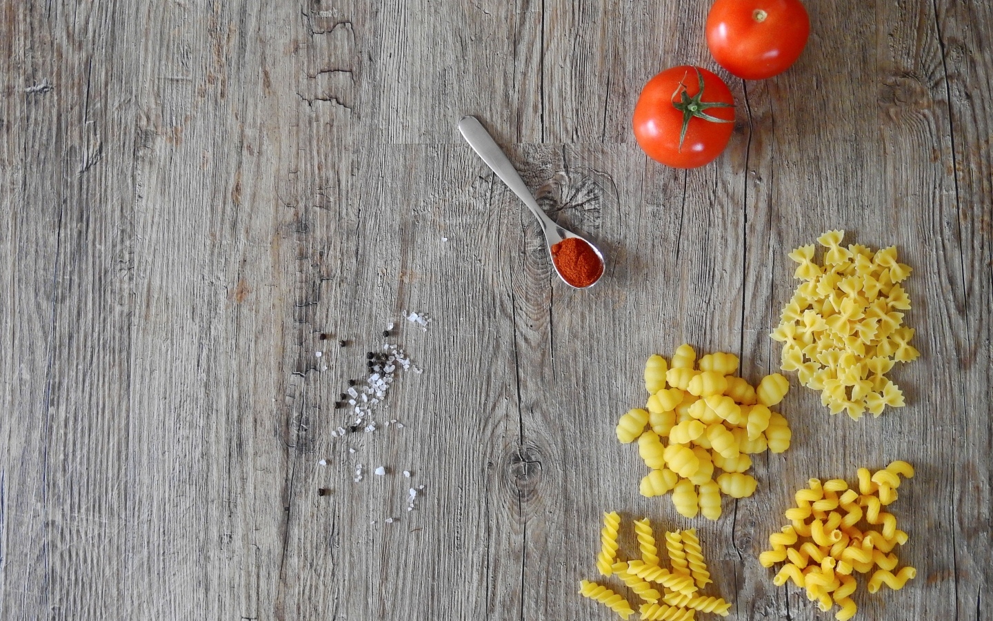 Разные виды макарон на столе с помидорами