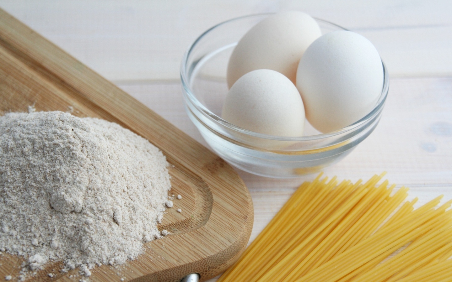 Яйца на столе с мукой и спагетти