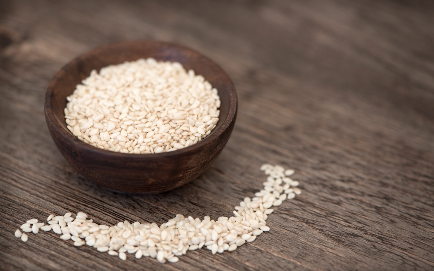 Зерна кунжута в деревянной миске на столе