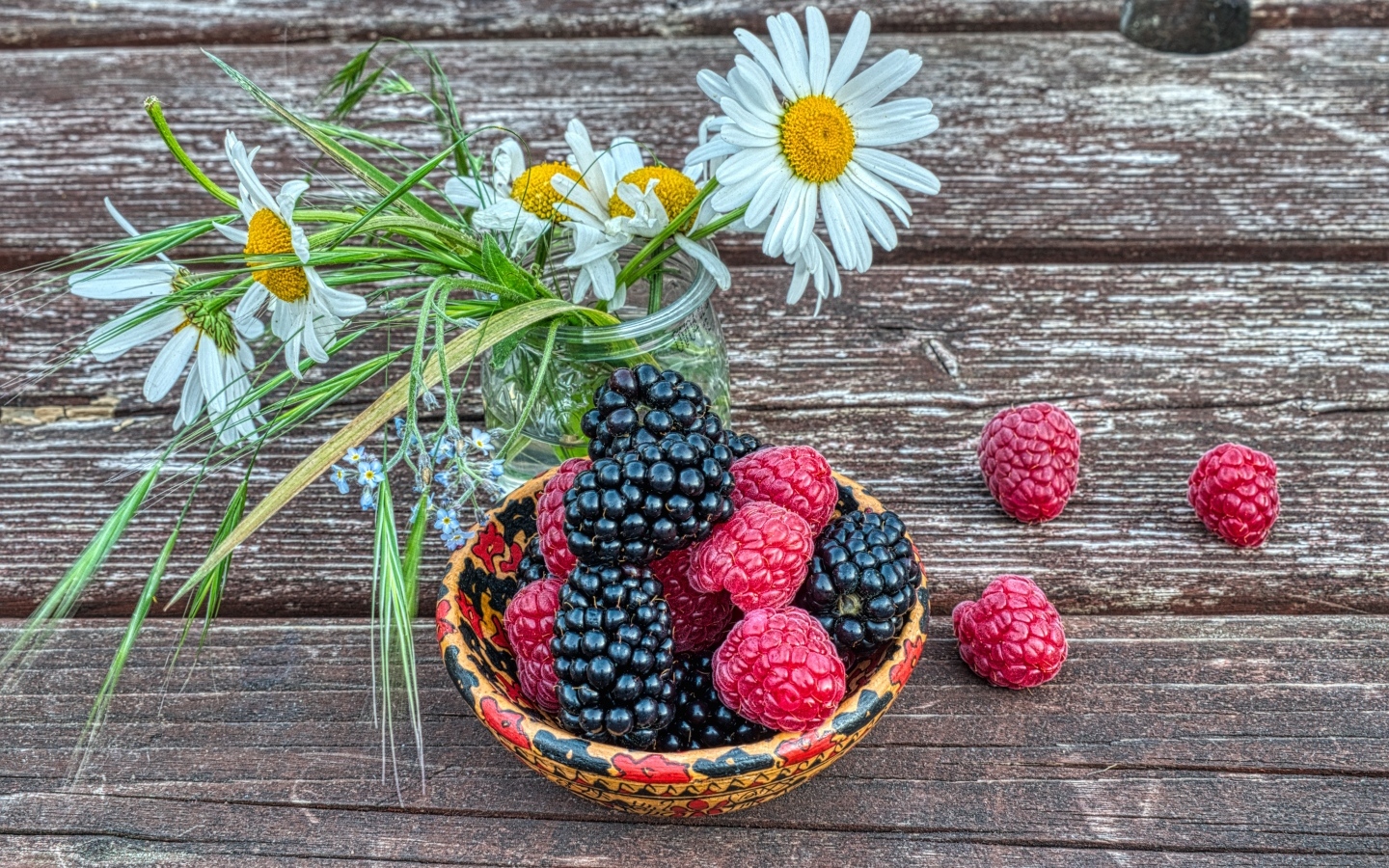 Ягоды черники и малины на столе с ромашками