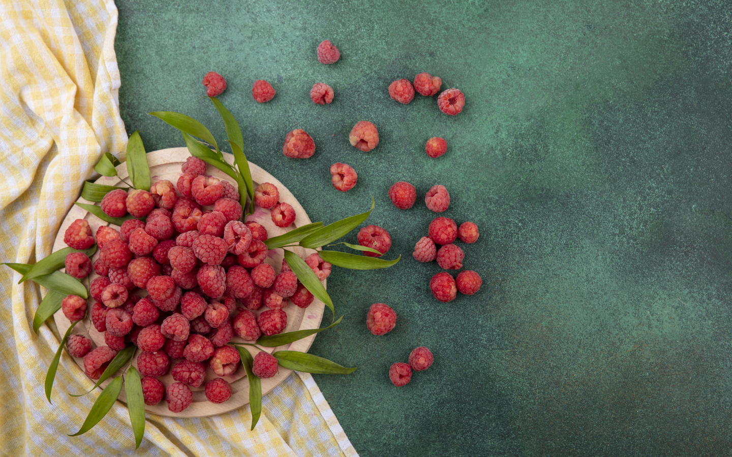 Красная малина с зеленой листвой на столе