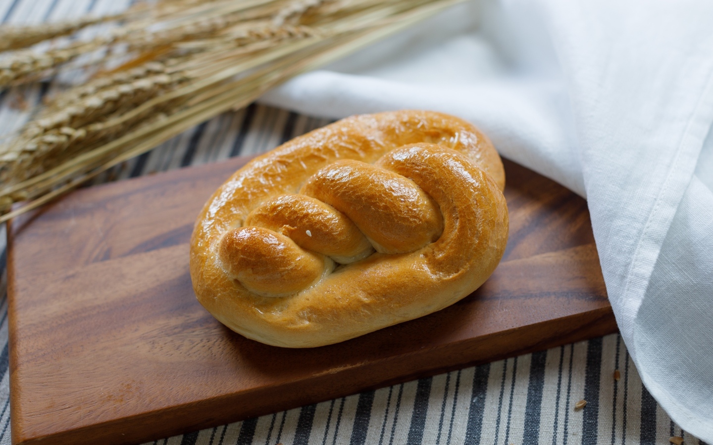 Булочка на столе с колосьями пшеницы