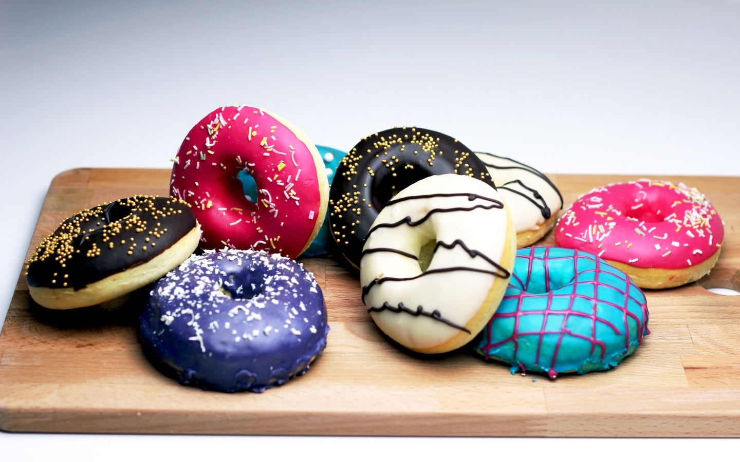 Аппетитные разноцветные пончики на деревянной доске