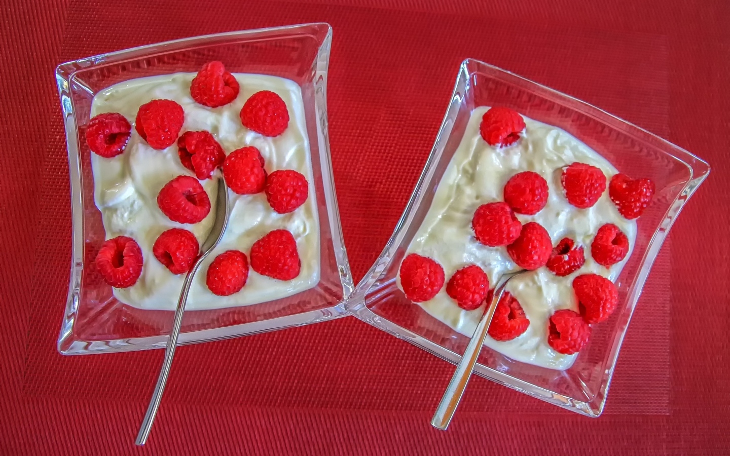 Десерт с ягодами малины на красном столе