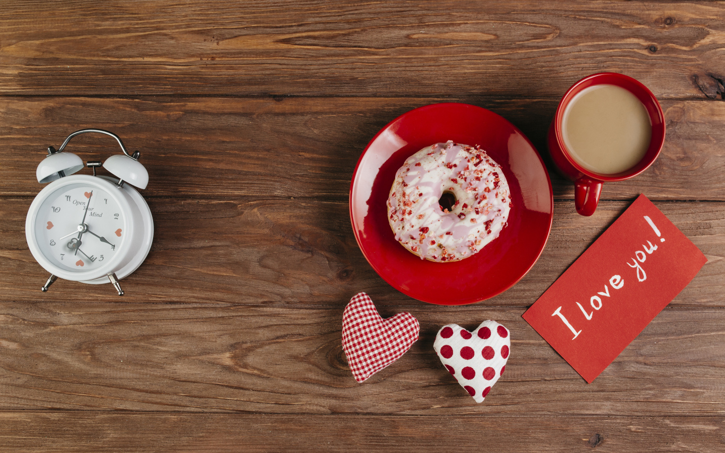 Пончик на столе с будильником, чашкой кофе и сердечками