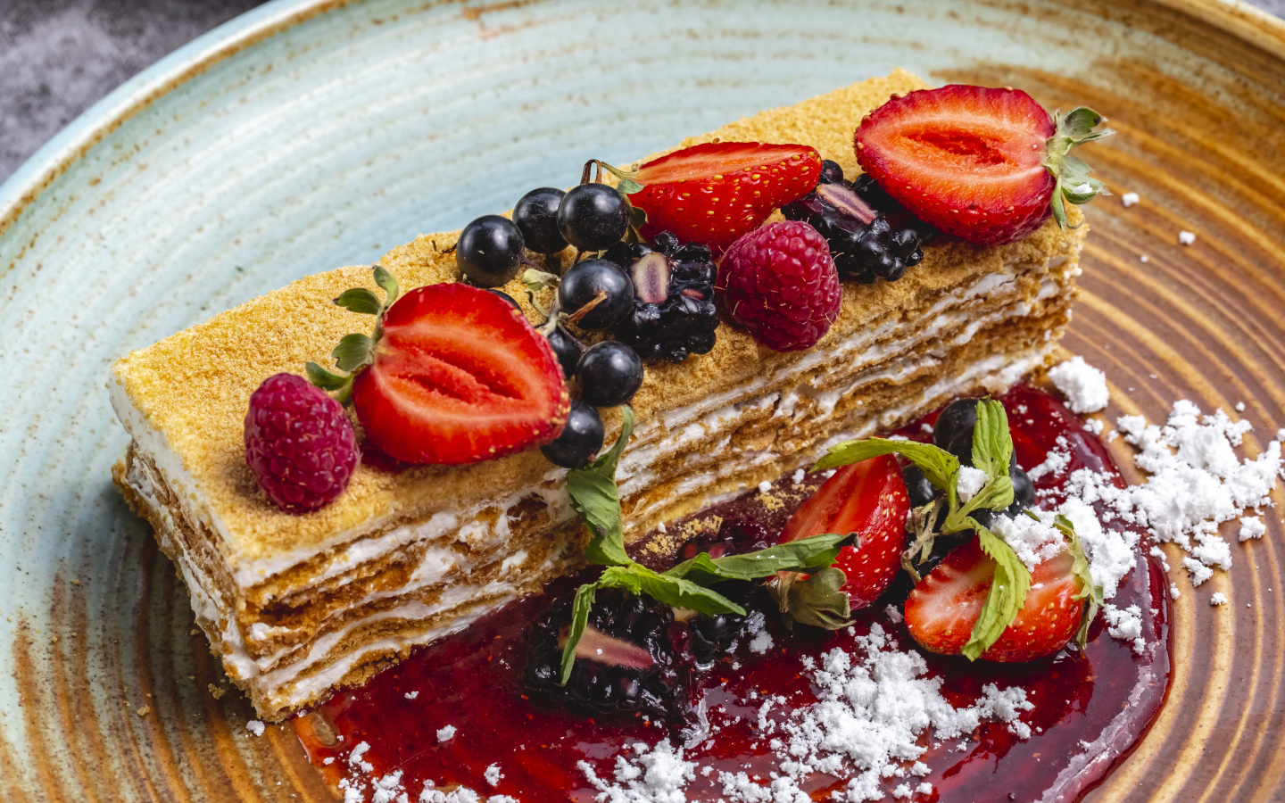 Большой кусок медового торта с ягодами