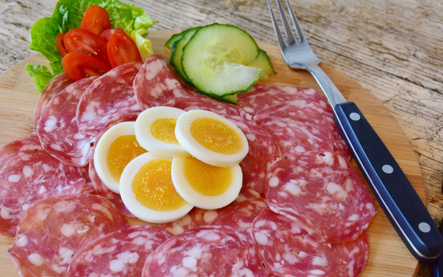 Колбаса салями на доске с вареными яйцами и овощами