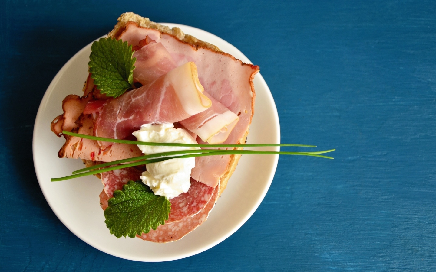 Бутерброд с колбасой и беконом на синем столе