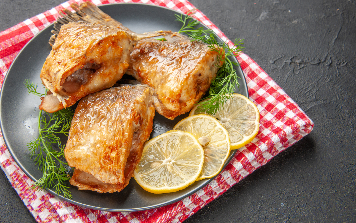 Куски жареной рыбы на тарелке с кусочками лимона и укропом