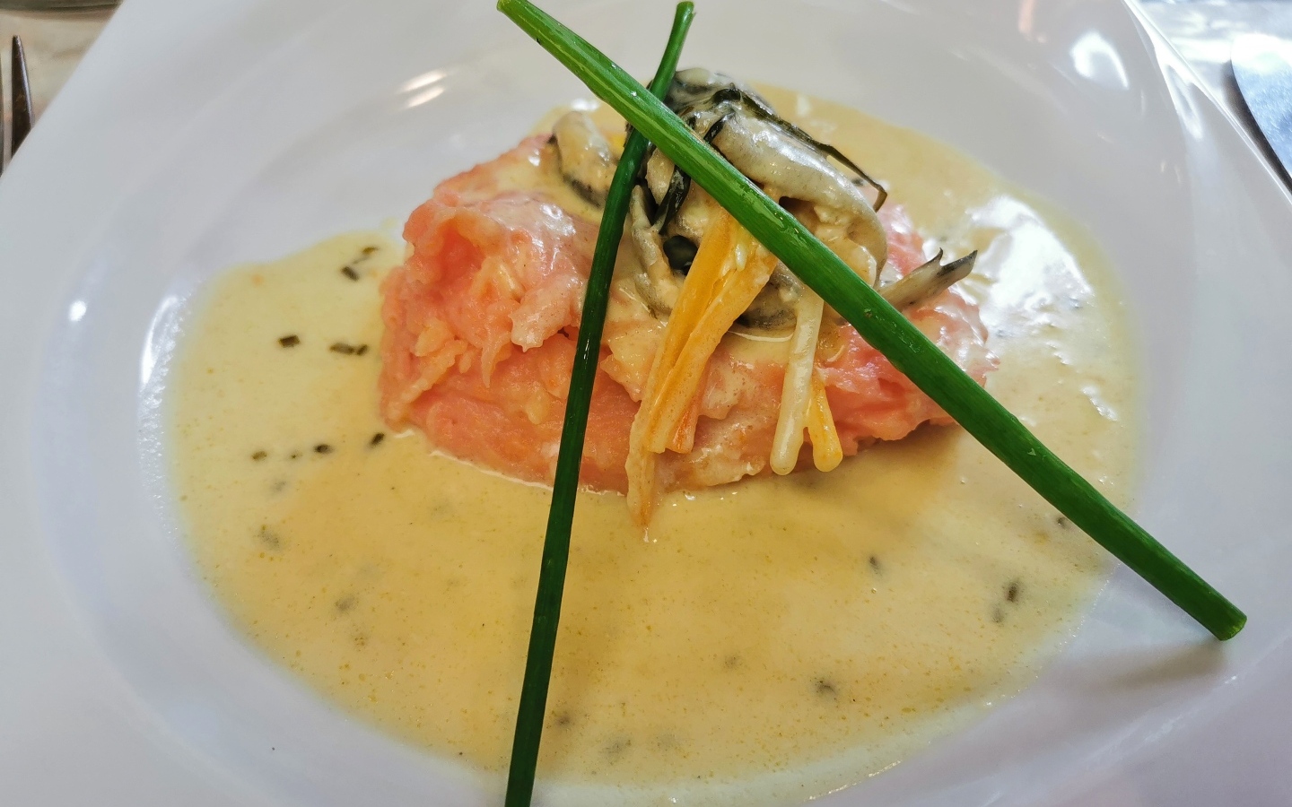 Красная рыба с соусом на тарелке с зеленым луком