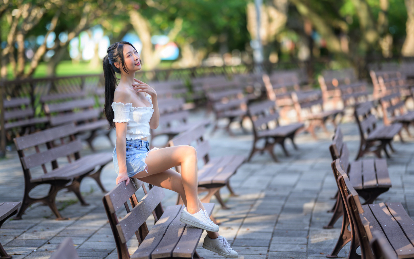 Спортивная азиатка сидит на лавке в парке