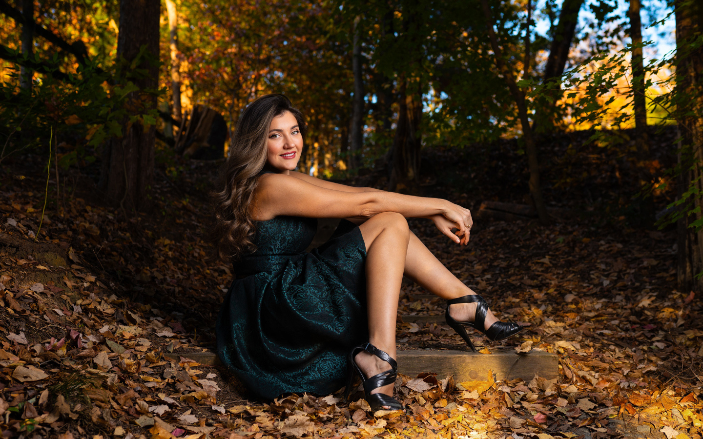 Красивая девушка в платье сидит на земле в осеннем парке