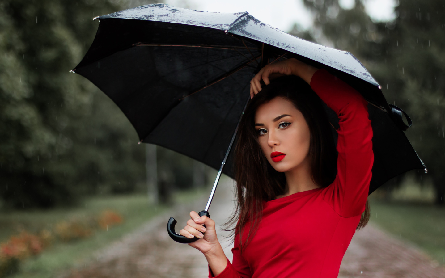 Красивая девушка в красном платье под черным зонтом