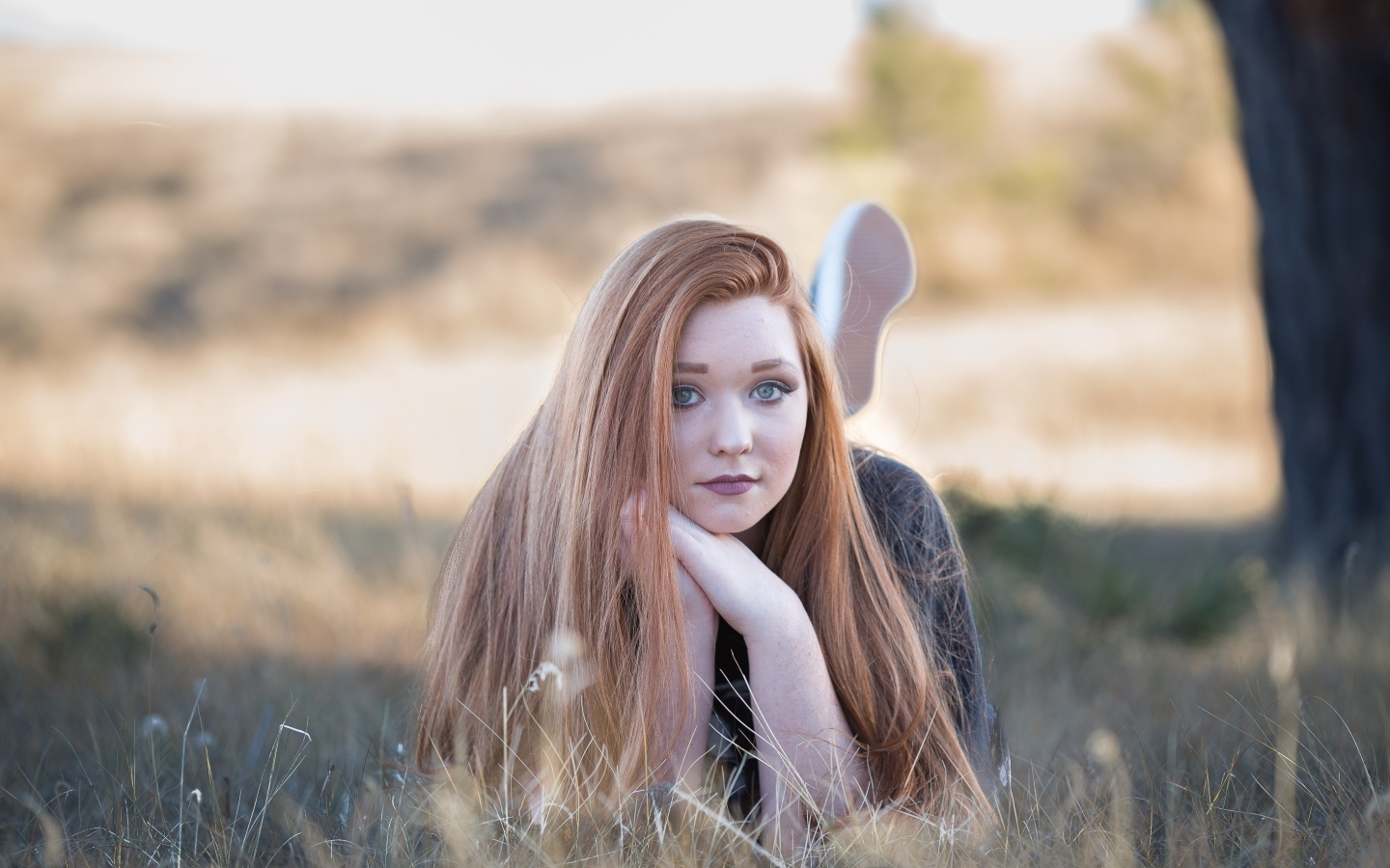 Красивая рыжеволосая девушка лежит на траве