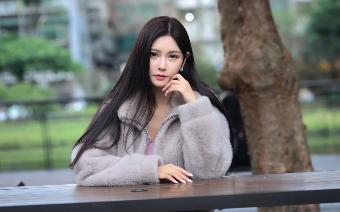 Кареглазая азиатка сидит в парке за столом