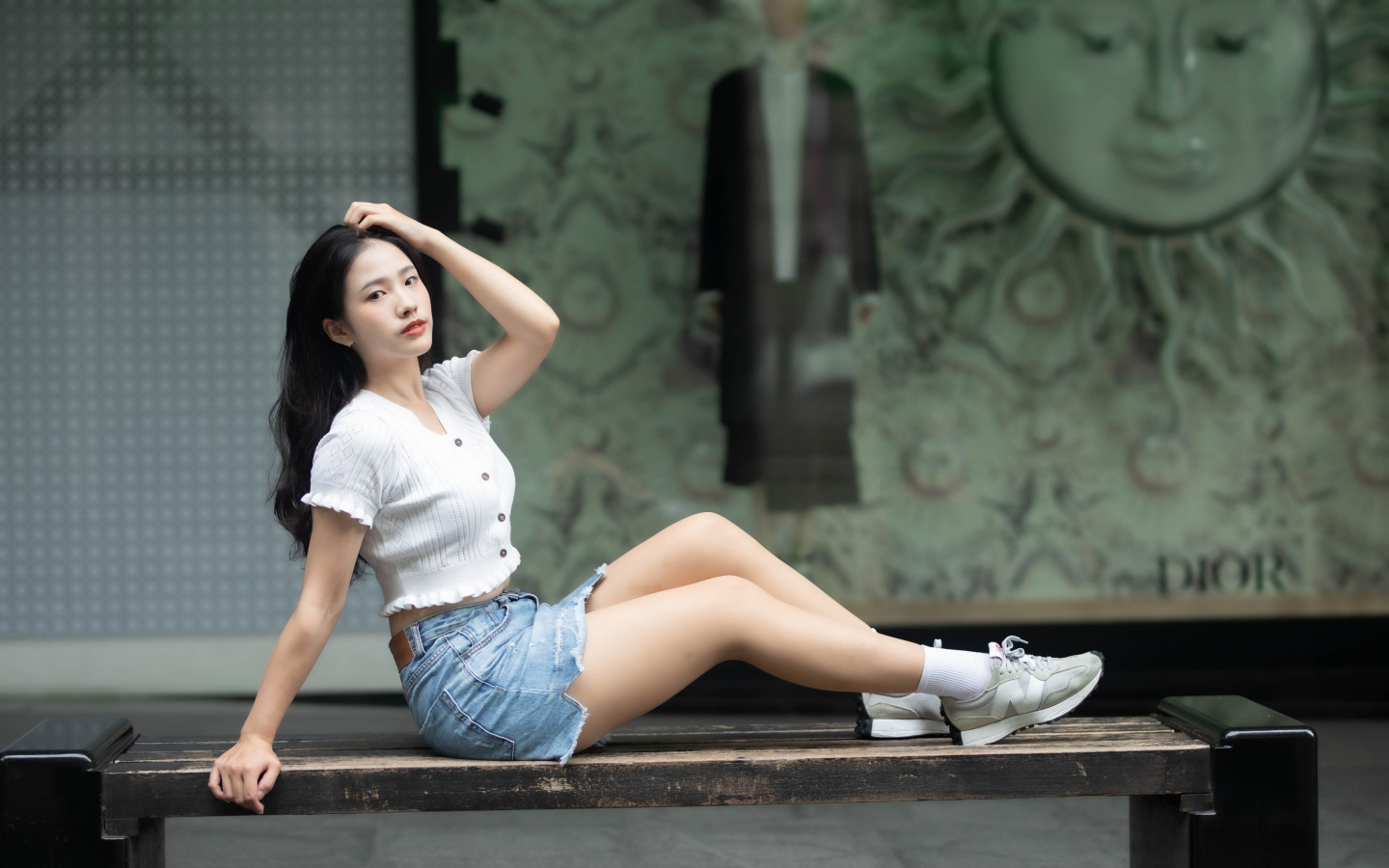 Милая девушка азиатка в белой кофте лежит на лавке