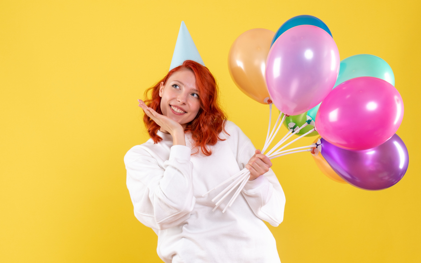 Милая рыжеволосая девушка с шариками на желтом фоне