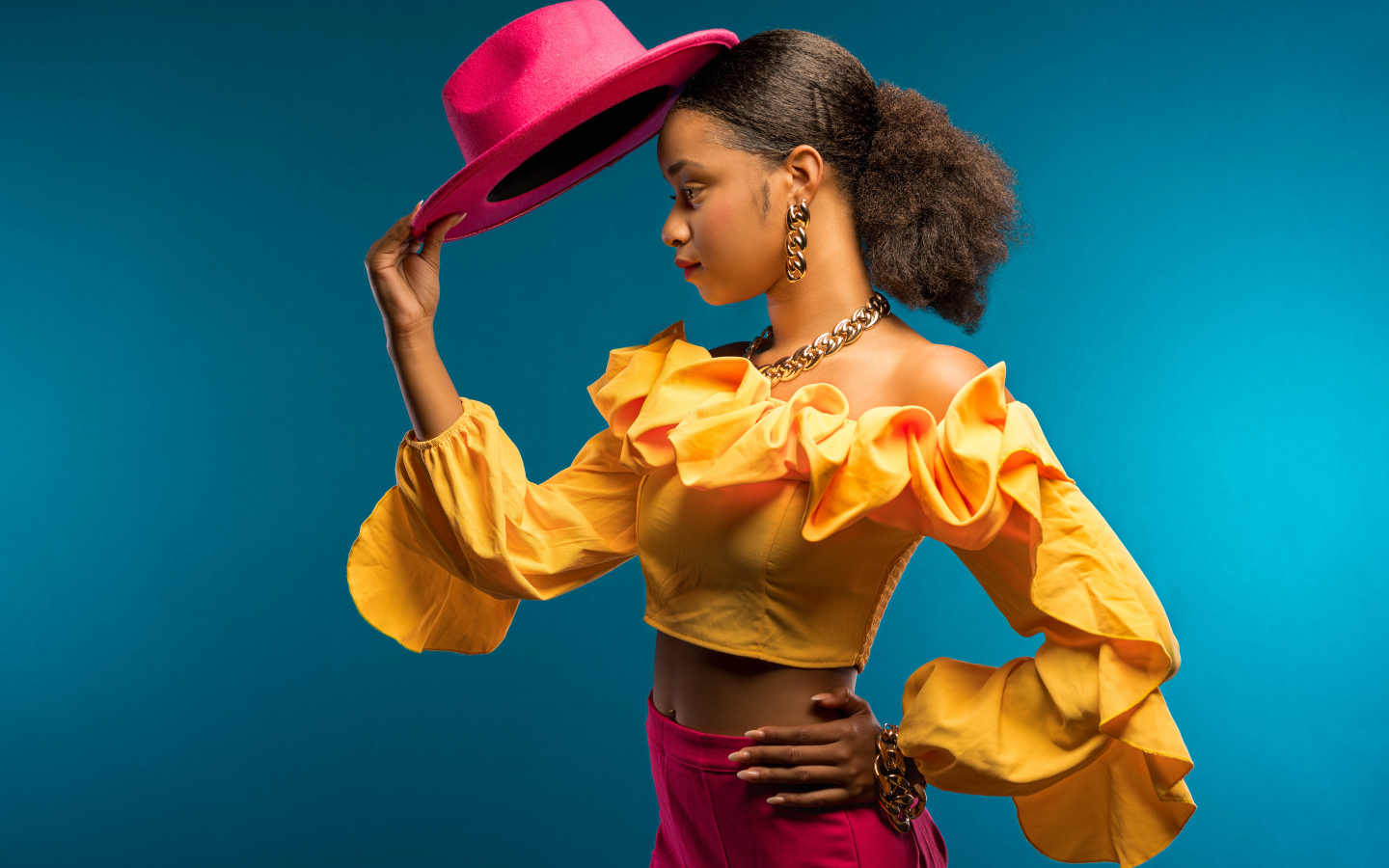 Темнокожая девушка в костюме с красной шляпой в руке