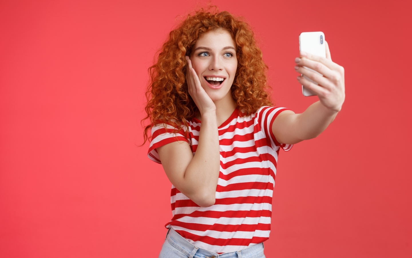 Девушка делает селфи на красном фоне