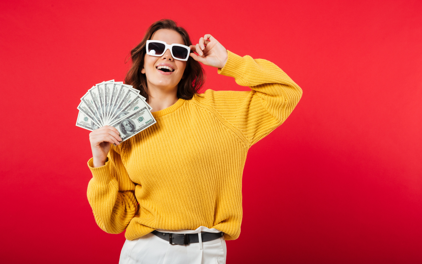 Девушка с веером из долларов на красном фоне