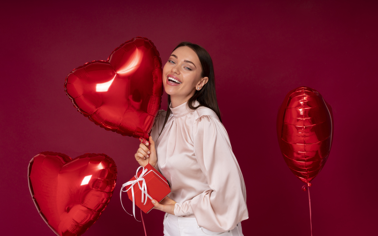 Девушка с шарами в форме сердца на красном фоне