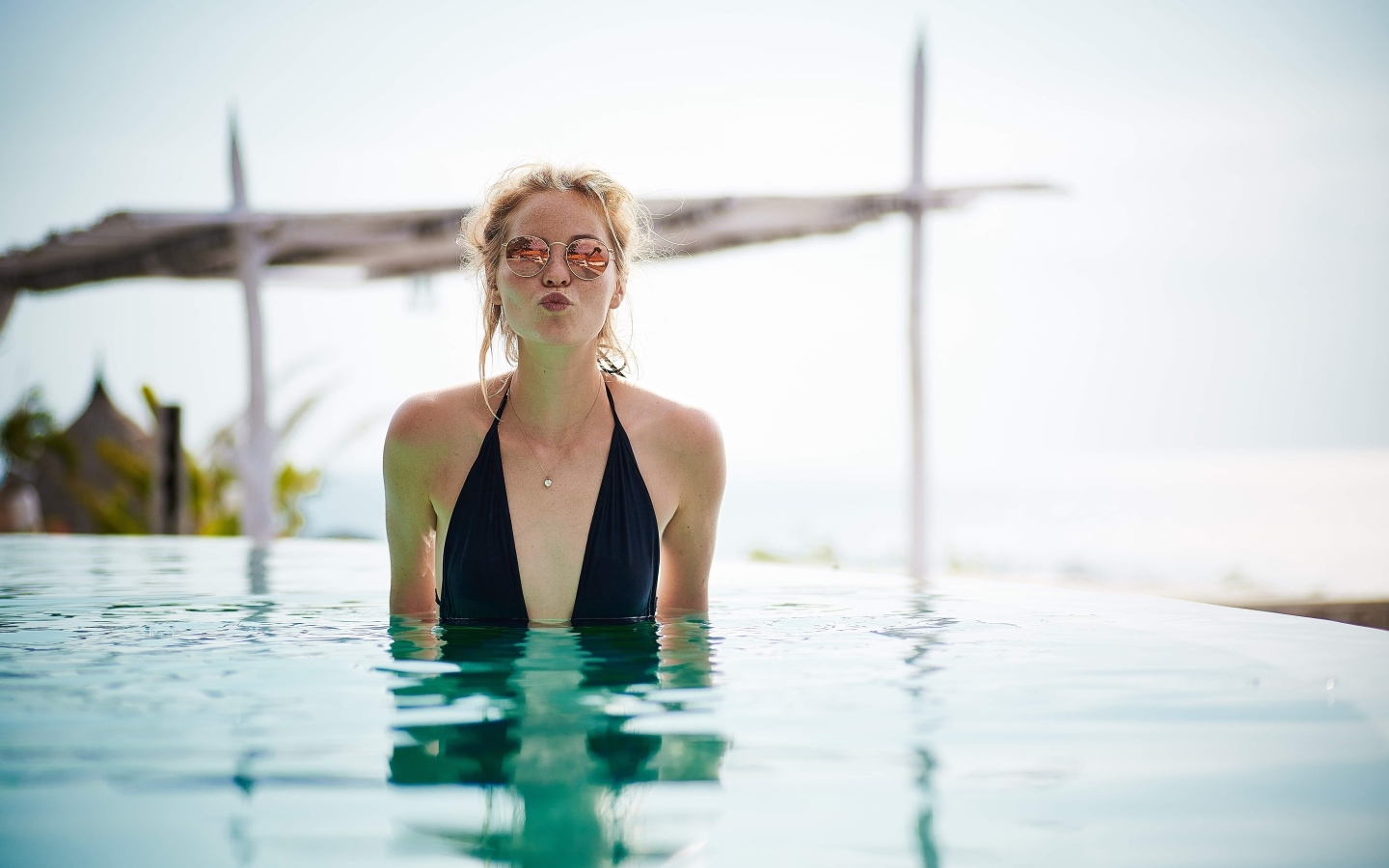 Довольная девушка в очках стоит в бассейне