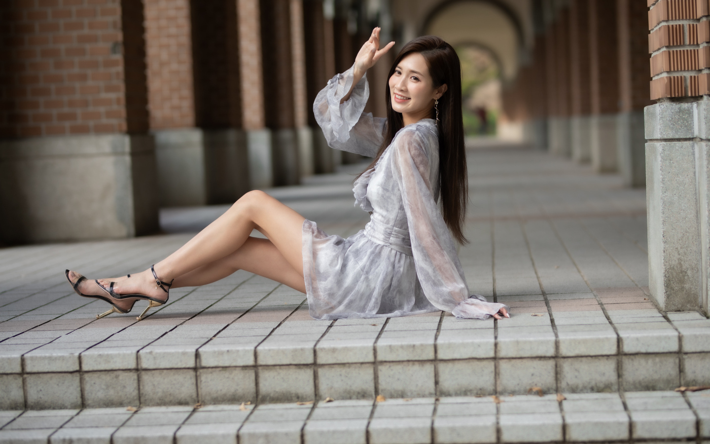 Улыбающаяся девушка азиатка сидит у ступеней