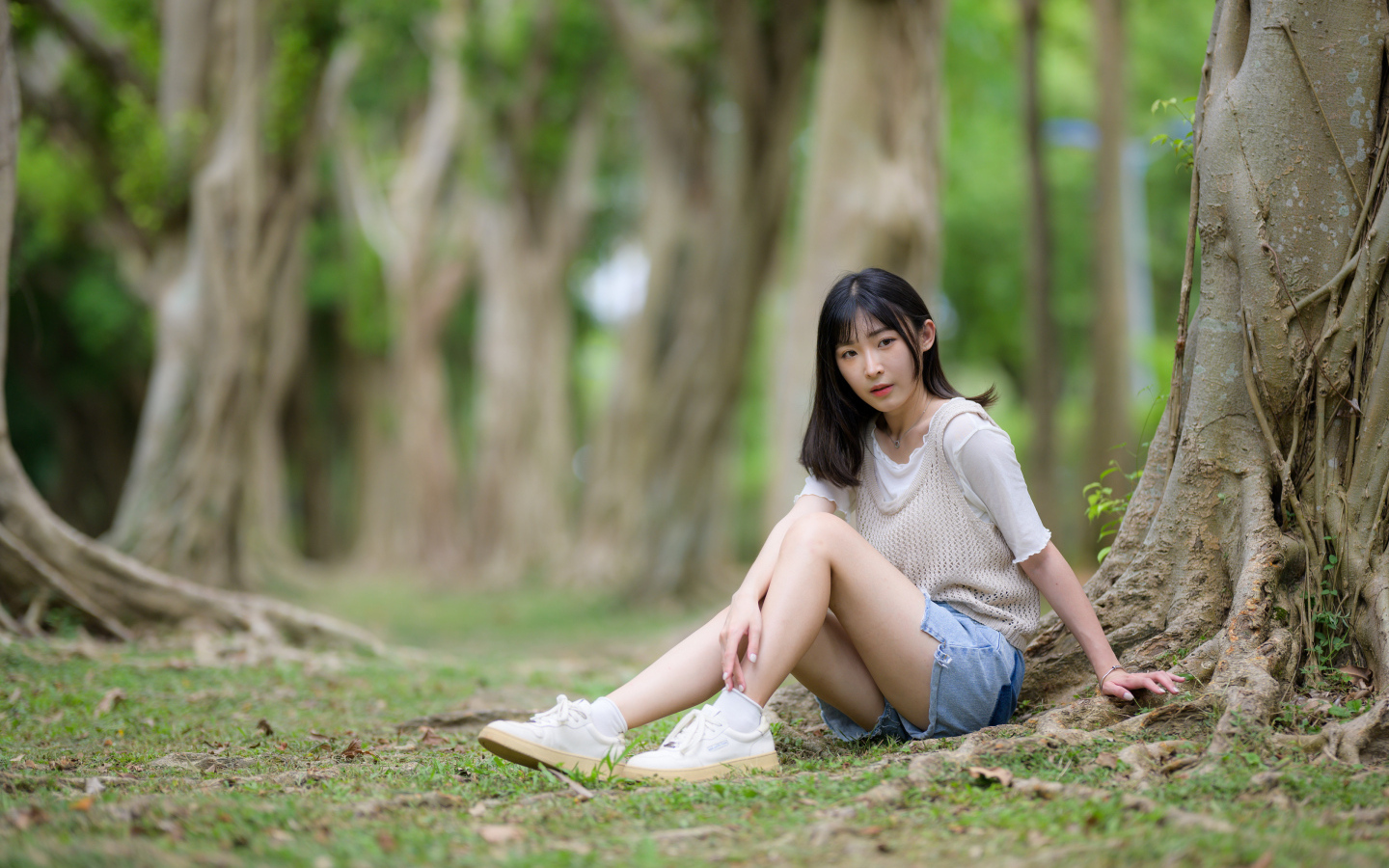 Молодая девушка азиатка сидит у дерева в парке