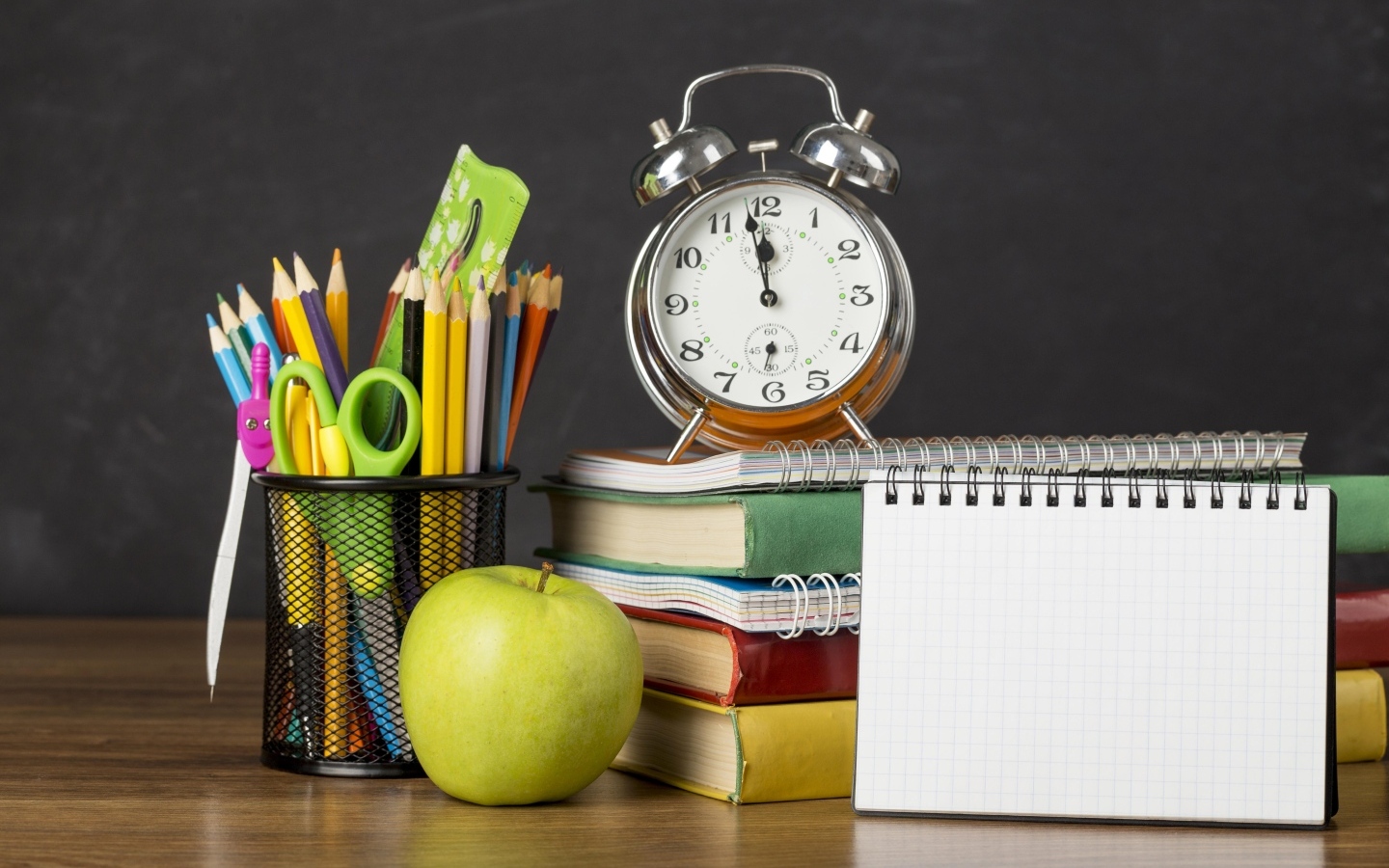 Канцелярские предметы на столе с будильником и книгами 