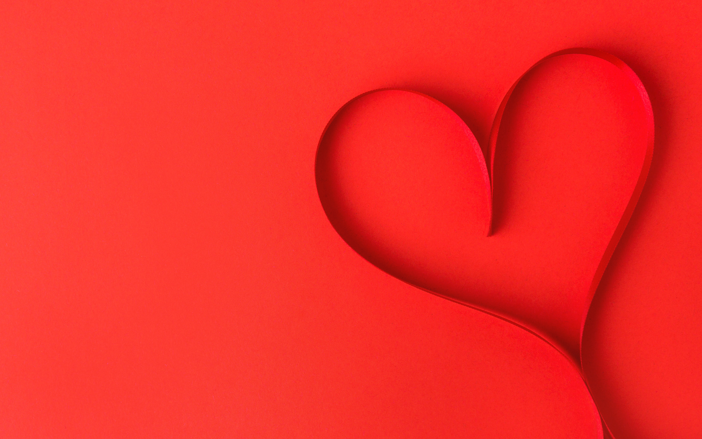 Сердце из атласной ленты на красном фоне