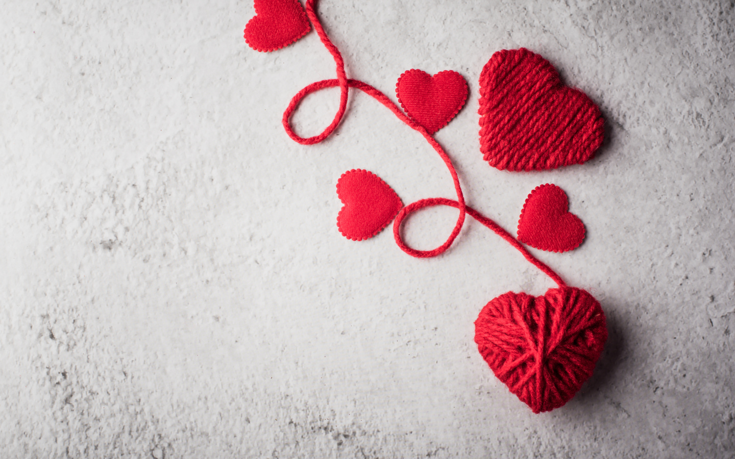 Сердечки из красной шерстяной нити на сером фоне
