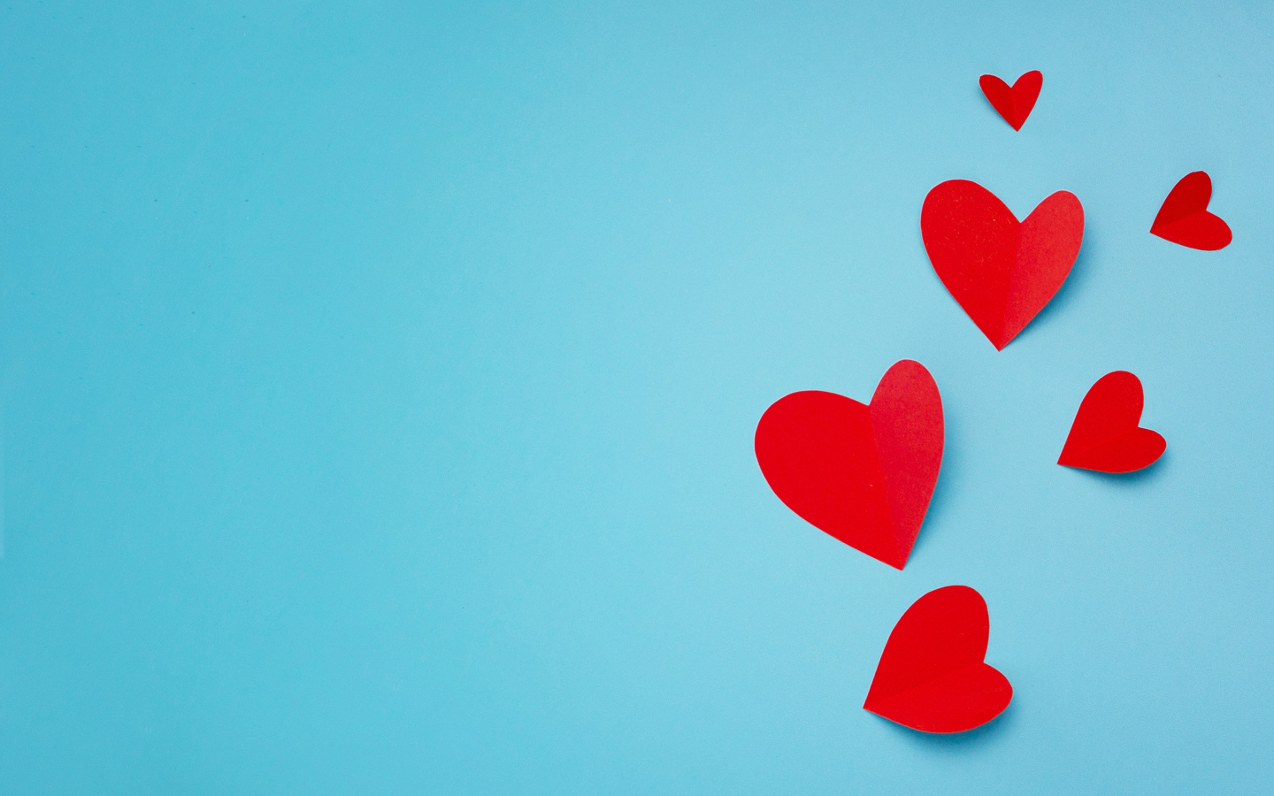 Много красных бумажных сердечек на голубом фоне