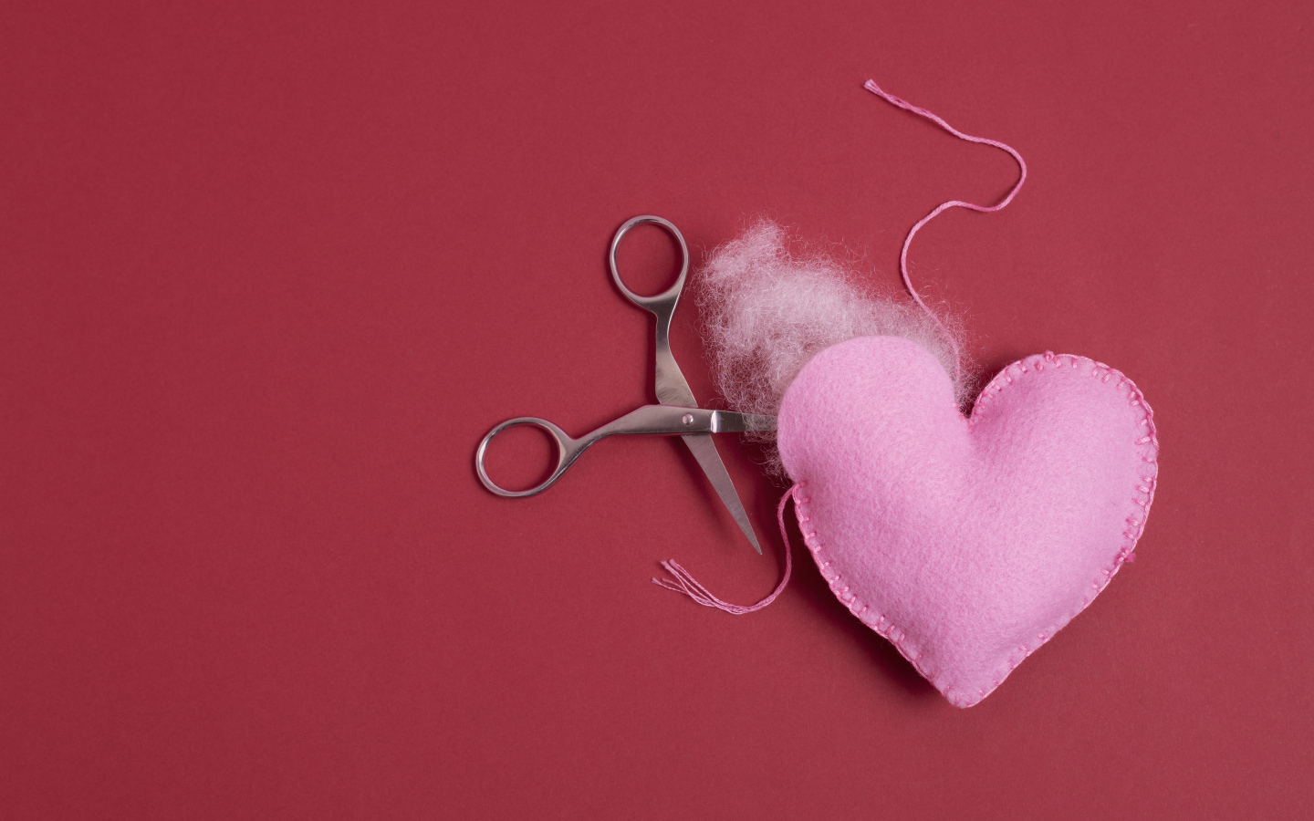 Розовое  сердце с ножницами на красном фоне