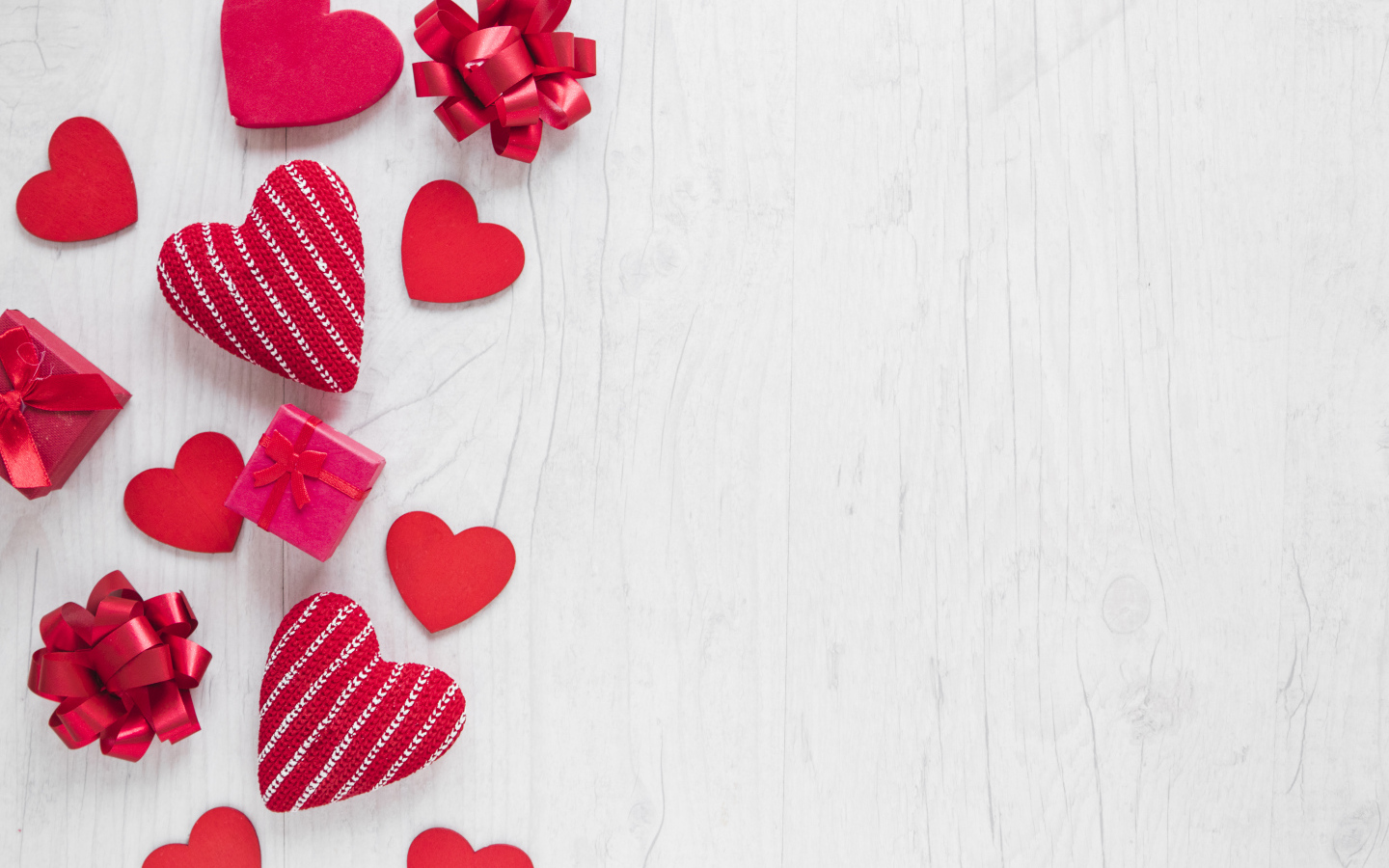 Красные сердечки с подарками и бантами на деревянном фоне