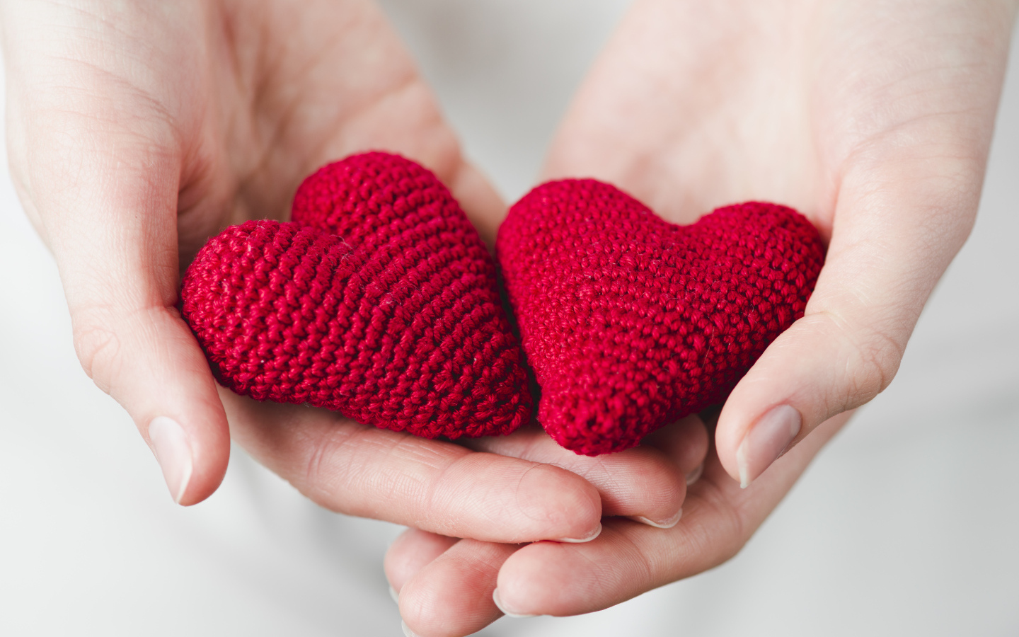 Два красных вязаных сердечка в руках девушки