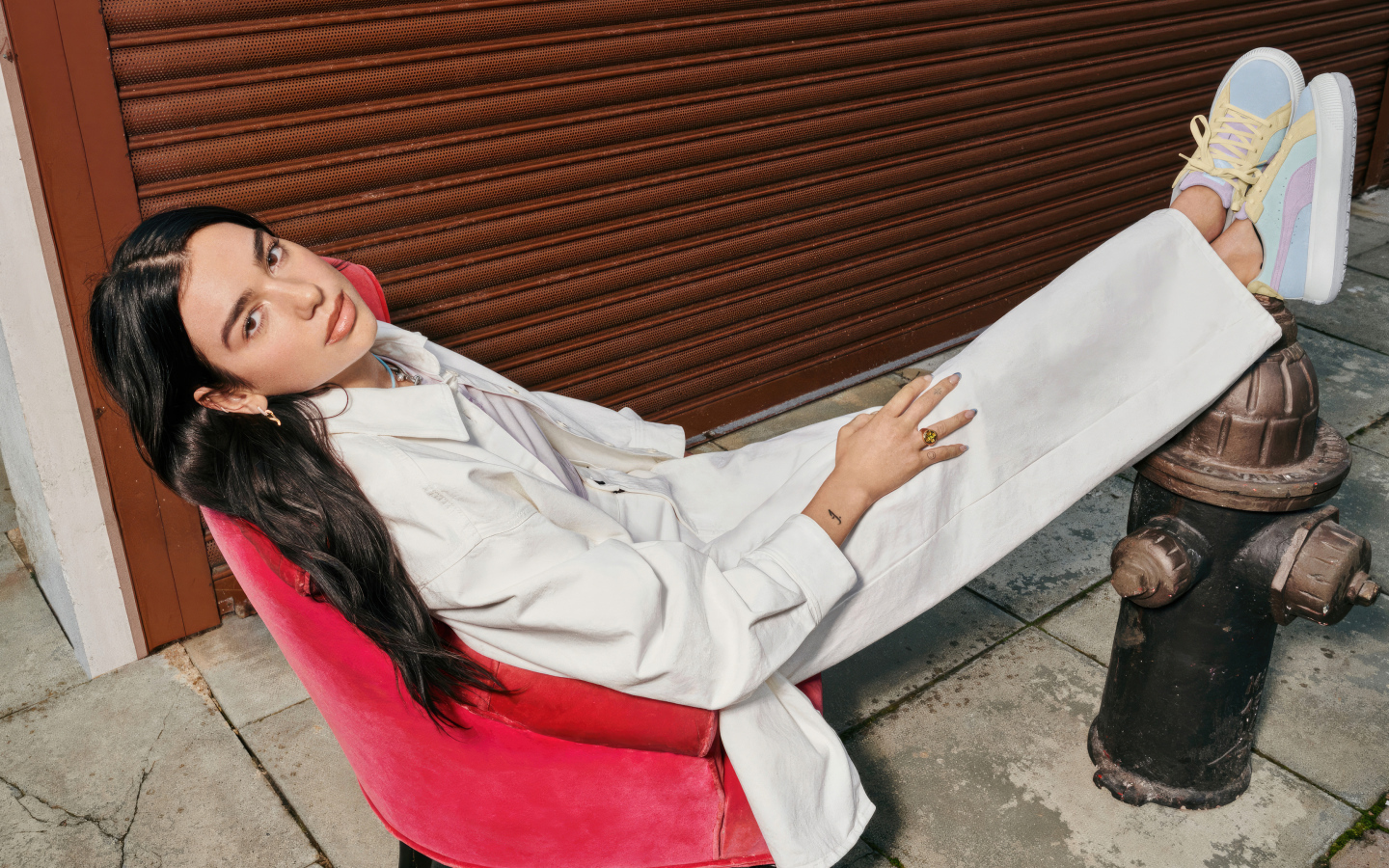 Певица Дуа Липа в белом костюме сидит в кресле