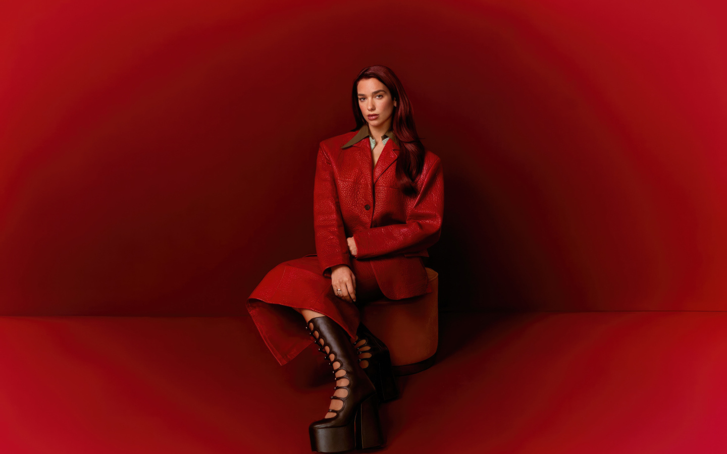 Певица Дуа Липа позирует на красном фоне