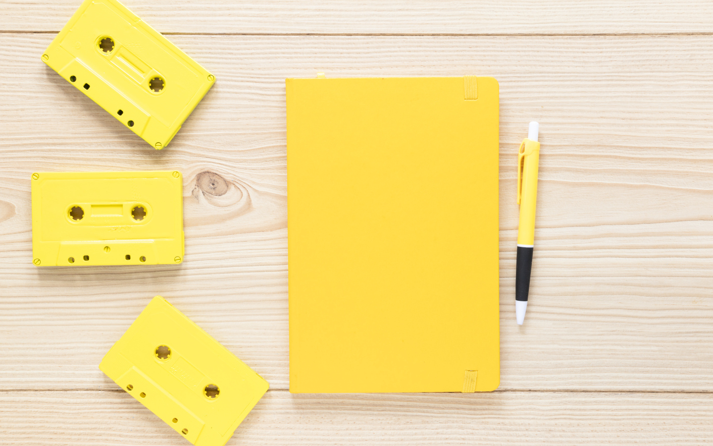 Желтый блокнот с ручкой и кассетами на столе